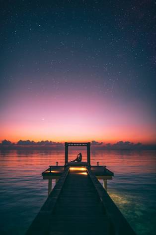 Best Spots for Deep Sea Fishing 1 a girl sitting on a boardwalk during sunset on the sea