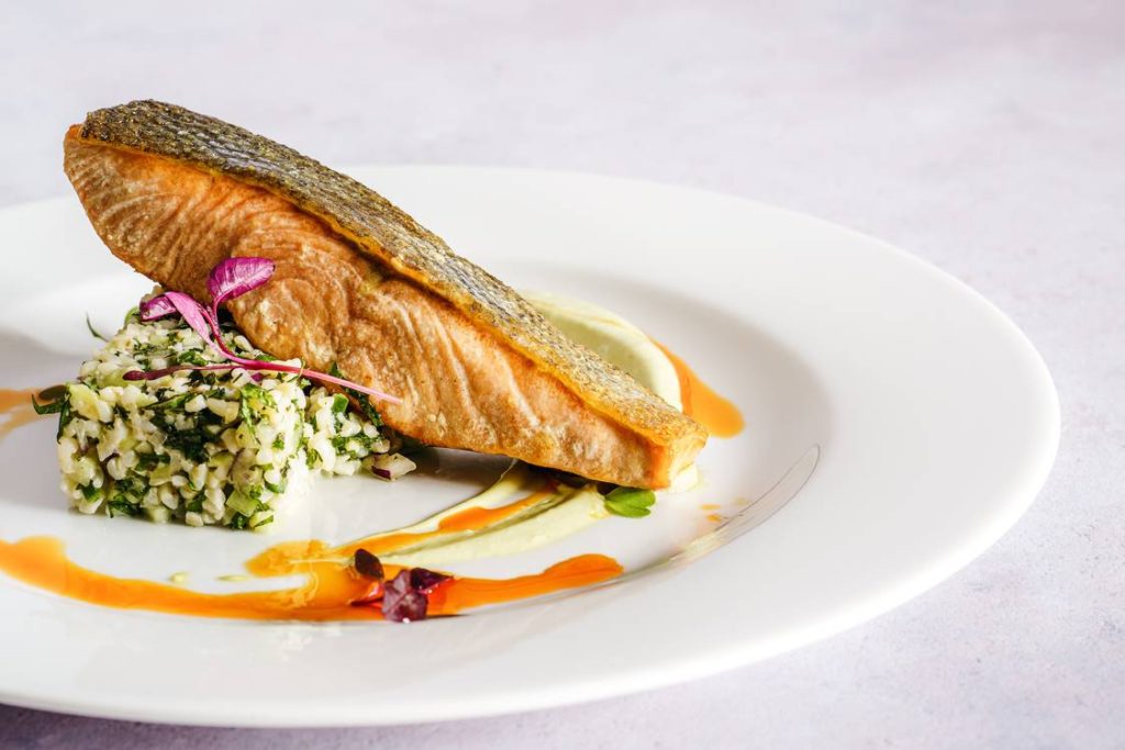 The Best Wines To Pair With Seafood 1 A fish steak served on a platter with an orange sauce.