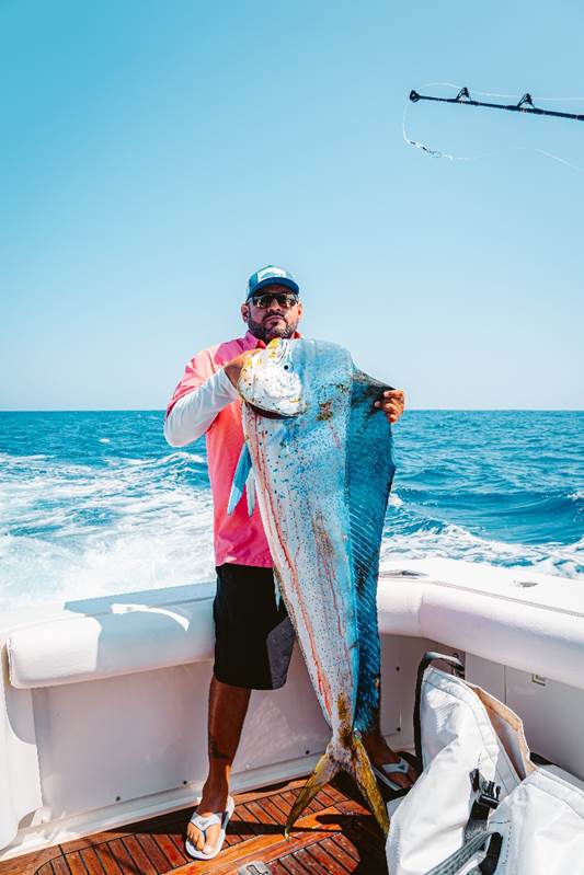 Is It Safe To Book A Fishing Trip To Cabo? 2 a fisherman holding a big fish that he caught on a fishing tour in Cabo San Lucas.